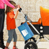 Matelas à langer portable AquaMom bleu suspendu au châssis d'une poussette lors d'une promenade en famille - Bébé Lova