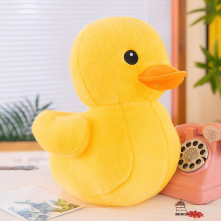 Mini peluche canard jaune kawaii posée sur un bureau avec téléphone rétro rose - Bébé Lova
