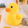 Mini peluche canard jaune kawaii posée sur un canapé avec décoration cosy - Bébé Lova