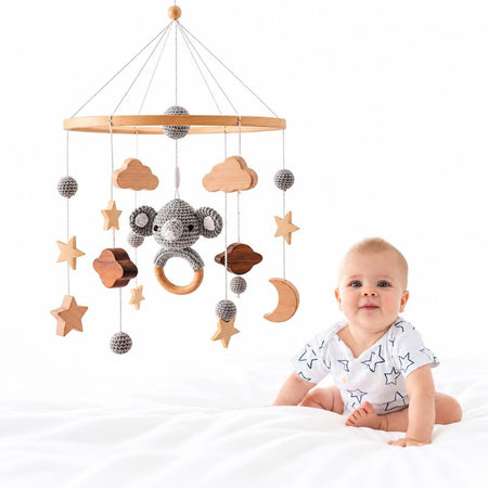 Mobile en bois Bellwood au-dessus d’un bébé endormi avec lumières tamisées - Bébé Lova