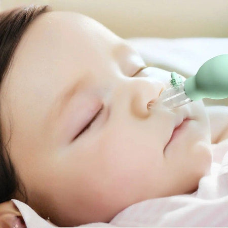 Mouche-bébé aspirateur nasal anti-reflux vert utilisé en douceur sur un bébé endormi - Bébé Lova