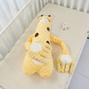 Peluche tapotante girafe jaune posée dans un lit bébé - Bébé Lova