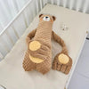 Peluche tapotante ours marron douce et apaisante posée dans un lit bébé - Bébé Lova