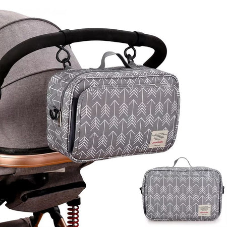 Sac organisateur de poussette gris à flèches accroché au guidon d'une poussette avec encart du sac - Bébé Lova