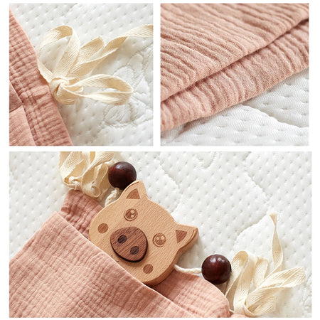 Gros plans sur les finitions de l'organiseur : nouettes, tissu gaze de coton et poche avec jouet en bois - Bébé Lova