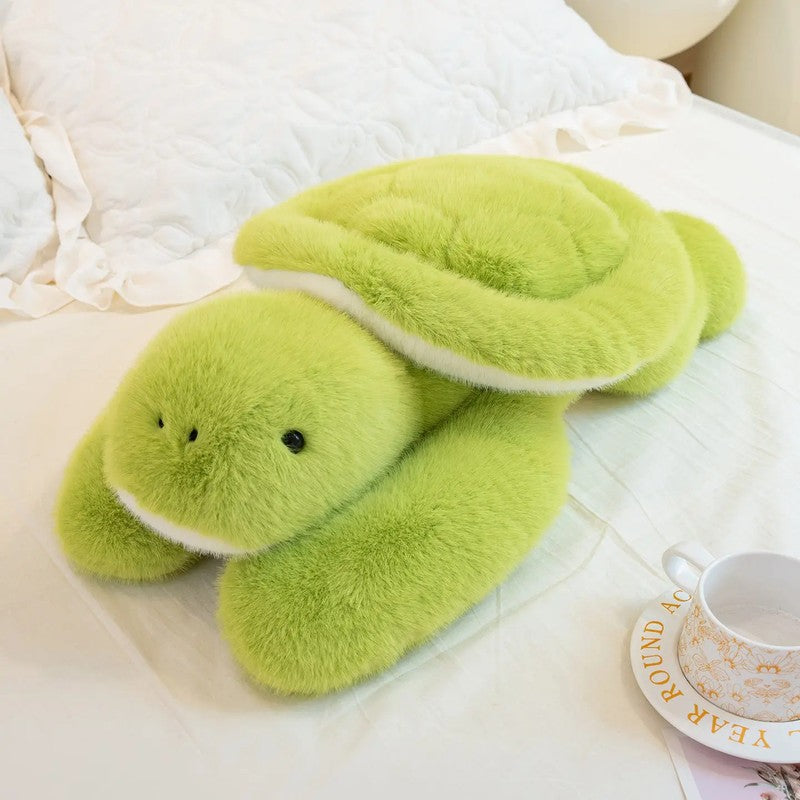 Peluche grenouille verte allongée sur un lit avec bras longs réconfortants - Bébé Lova