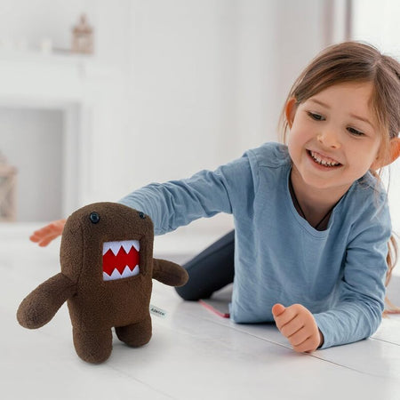 Petite fille jouant avec une peluche monstre kawaii marron Funny Domo dans une chambre lumineuse - Bébé Lova