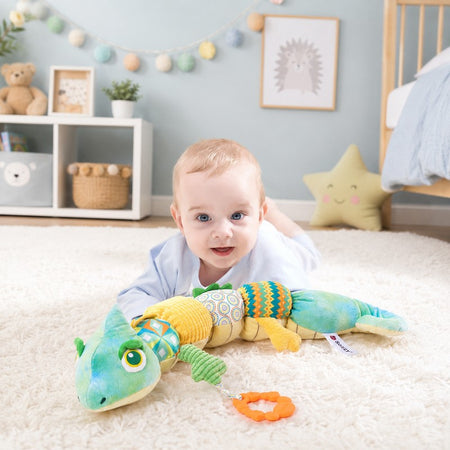 Bébé allongé dans une chambre d’enfant avec la peluche musicale caméléon sensorielle - Bébé Lova
