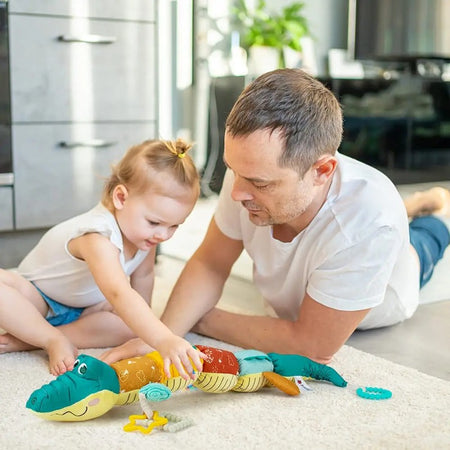 Papa et petite fille jouant avec la peluche musicale crocodile MusicGator sur un tapis de salon - Bébé Lova