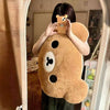 Coussin peluche ours géant tenu devant un miroir dans une chambre cosy - Bébé Lova