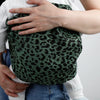 Gros plan sur bébé installé dans la poche du porte-bébé à bandoulière léopard vert - Bébé Lova