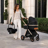 Maman transportant le cosy à côté de la poussette 3 en 1 lors d'une promenade - Bébé Lova