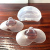 Deux protège-mamelons en silicone à côté de leur boîte de rangement sur une table en bois - Bébé Lova