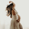 Portrait artistique d’une femme enceinte en robe beige fluide sur fond clair - Bébé Lova