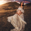 Future maman tatouée portant une robe crème fluide lors d’un shooting grossesse en extérieur - Bébé Lova