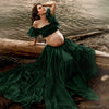 Femme enceinte en robe verte élégante assise près d’un lac pour séance photo maternité - Bébé Lova