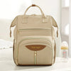 Sac à dos à langer beige PackaMom présenté de face avec un biberon - Bébé Lova