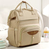 Sac à dos à langer beige vu de trois quarts montrant ses multiples poches zippées et finitions dorées - Bébé Lova