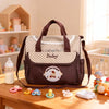 Sac à langer BearBag marron présenté avec accessoires pour bébé sur une table - Bébé Lova