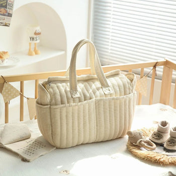 Sac à langer beige posé dans une chambre de bébé au style naturel et chaleureux - Bébé Lova
