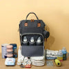 Sac à langer gris ouvert avec porte-biberons et accessoires de bébé disposés autour - Bébé Lova
