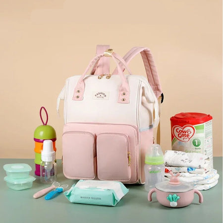 Sac à langer rose entouré d'accessoires de bébé : biberons, lait, lingettes et couches - Bébé Lova