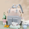 Sac à langer rose et bleu présenté sur une table avec biberons et accessoires de bébé - Bébé Lova