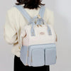 Femme portant le sac à langer crème et bleu sur le dos - Bébé Lova