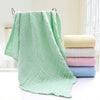 Grande serviette bébé verte suspendue avec pile de coloris pastel - Bébé Lova