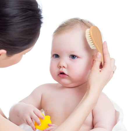 Maman utilisant une brosse douce en bois sur les cheveux de son bébé - Bébé Lova