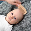 Bébé allongé pendant le coiffage avec peigne en bois naturel pour nourrisson - Bébé Lova
