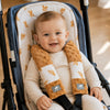 Gros plan sur un bébé souriant en poussette portant les protège-ceintures minky motif feuilles ocre - Bébé Lova
