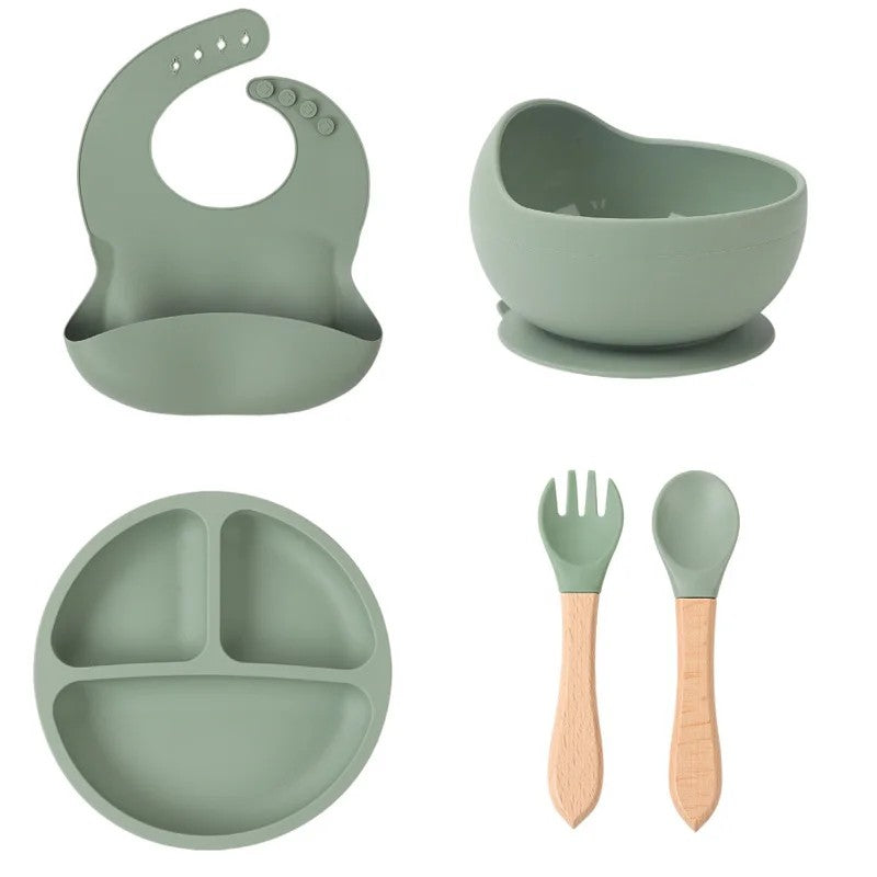 Set de vaisselle bébé en silicone vert sauge : bavoir, bol à ventouse, assiette compartimentée, fourchette et cuillère à manche bois - Bébé Lova