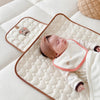 Bébé allongé à côté du tapis à langer plié à broderie tigre - Bébé Lova