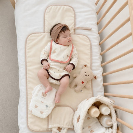 Bébé endormi sur le tapis à langer matelassé dans son berceau avec peluche et panier - Bébé Lova
