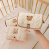 Trois tapis à langer pliés tenus à la main au-dessus d'un berceau - Bébé Lova