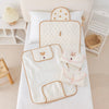 Vue de dessus de deux tapis à langer dépliés et deux pochettes pliées sur un lit - Bébé Lova