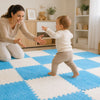 Bébé faisant ses premiers pas vers sa maman sur un tapis puzzle CozyMat bleu et blanc - Bébé Lova