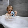 Thermomètre de bain bébé bleu tenu par un enfant dans un bain moussant - Bébé Lova