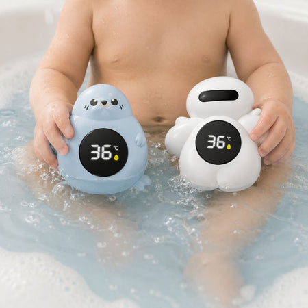 Thermomètre de bain bébé tenu par un bébé dans le bain en coloris bleu et blanc affichant 36°C - Bébé Lova