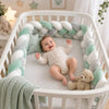 Bébé dans un lit à barreaux avec tour de lit tressé blanc dans une chambre décorée de fleurs roses - Bébé Lova