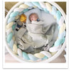 Bébé endormi dans un couffin rond entouré d’un tour de lit tressé multicolore pastel - Bébé Lova