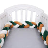 Tour de lit tressé vert sapin, caramel et blanc présenté dans un berceau bébé - Bébé Lova