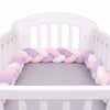 Tour de lit tressé lilas, rose pastel et blanc présenté dans un berceau bébé - Bébé Lova