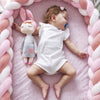 Bébé dormant dans un couffin entouré d’un tour de lit tressé rose poudré et blanc - Bébé Lova