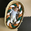 Nouveau-né installé dans un couffin avec tour de lit tressé vert sauge, caramel et blanc - Bébé Lova