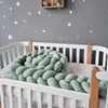 Tour de lit tressé vert sauge présenté enroulé pour un rangement facile - Bébé Lova