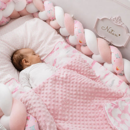 Bébé endormi avec tour de lit tressé rose et blanc à motifs dans un lit bébé cosy - Bébé Lova