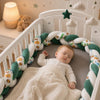 Bébé dormant paisiblement avec tour de lit tressé vert et blanc à motifs animaux - Bébé Lova