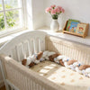Tour de lit tressé beige et blanc avec motifs animaux dans un lit bébé en osier - Bébé Lova